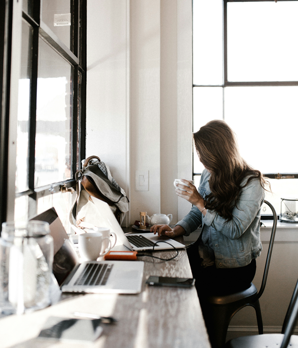 Girl working on a laptop drinking a cup of coffee.